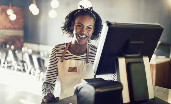 Happy business owner using the Dukamax POS system at checkout